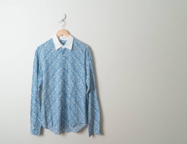 hanging blue shirt with wood hanger on wall
