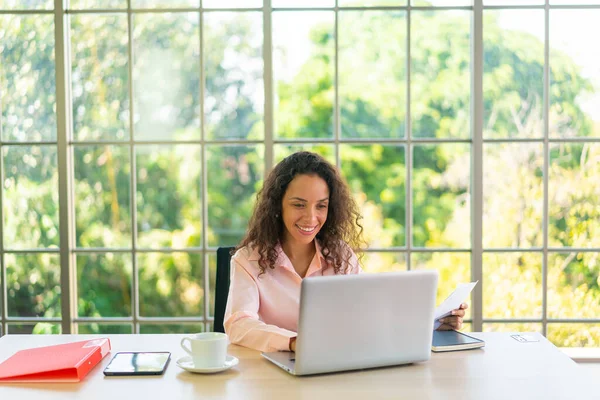 Latin kadın dizüstü bilgisayar ve kağıtlarla çalışıyor.