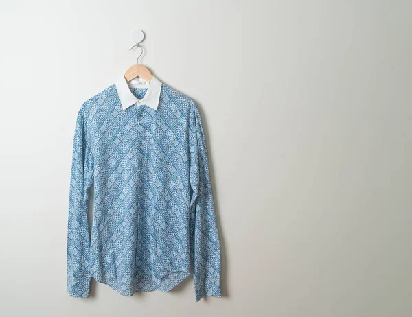 hanging blue shirt with wood hanger on wall