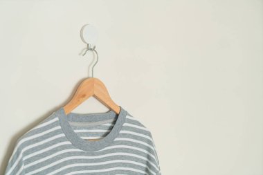 grey t-shirt hanging with wood hanger on wall