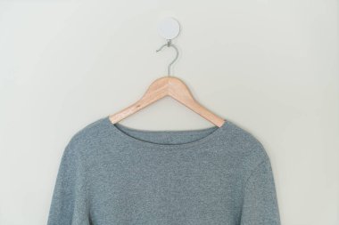 grey t-shirt hanging with wood hanger on wall