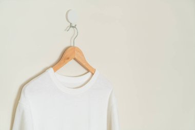 white t-shirt hanging with wood hanger on wall