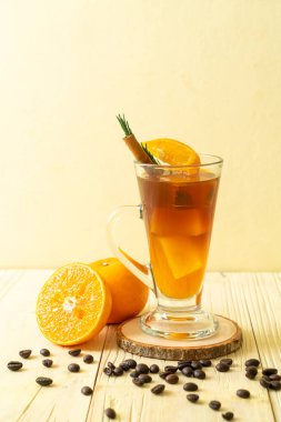 Bir bardak buzlu americano sade kahve ve biberiye ve tarçınla süslenmiş portakal ve limon suyu.