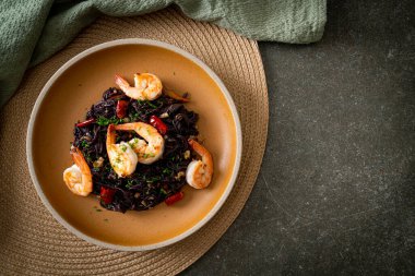 Sarımsaklı ve karidesli kızarmış siyah spagetti.