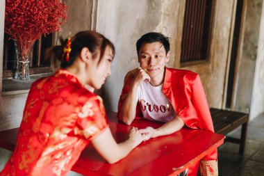 Mutlu genç Asyalı çiftler geleneksel Çin elbiseleriyle sevişir. Kırmızı, geleneksel bayramın ana rengidir. Buna Çin 'de düğün de dahil..