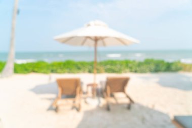 Arka planda plaj sandalyesi ve okyanus denizi olan soyut bulanık şemsiye