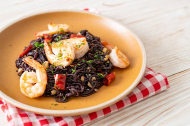 Sarımsaklı ve karidesli kızarmış siyah spagetti.