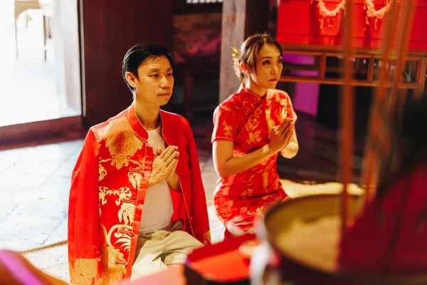 Happy young Asian couple love in Chinese traditional dresses praying at Chinese temple