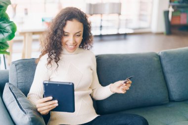 Tablet kullanan Latin bir kadın kredi kartı kullanıyor - İnternet üzerinden alışveriş kavramı