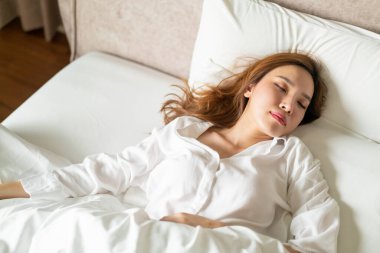 Beyaz yastıkla uyuyan güzel Asyalı kadın portresi.