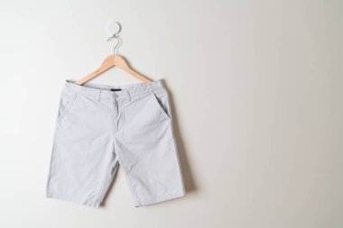 Kısa pantolon duvarda ahşap bir askıyla asılı.