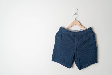 Kısa pantolon duvarda ahşap bir askıyla asılı.