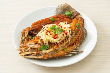 Balık soslu kızarmış deniz levreği balığı ve tabakta baharatlı salata.