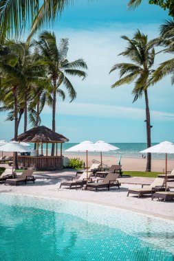 Plaj geçmişine sahip otel havuzunda yüzme havuzu etrafında plaj sandalyesi - tatil ve tatil kavramı
