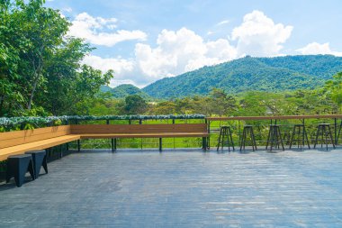 Balkonda boş bir bank ve bar taburesi var.