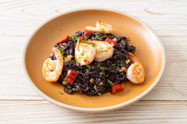 Sarımsaklı ve karidesli kızarmış siyah spagetti.