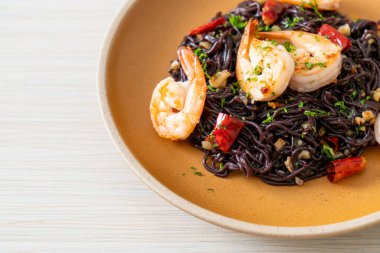 Sarımsaklı ve karidesli kızarmış siyah spagetti.