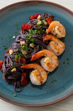 Sarımsaklı ve karidesli kızarmış siyah spagetti.