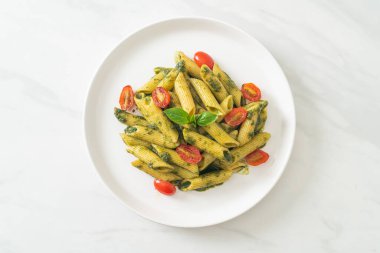 Pesto soslu ve domatesli makarna. Vejetaryen ve vejetaryen yemek tarzı.