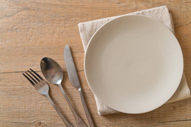 Ahşap zemin üzerinde bıçak, çatal ve kaşık olan boş tabak veya tabak