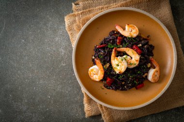 Sarımsaklı ve karidesli kızarmış siyah spagetti.