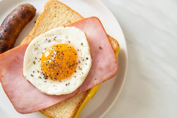 homemade bread toasted cheese topped ham and fried egg with pork sausage for breakfast