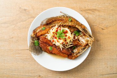 Balık soslu kızarmış deniz levreği balığı ve tabakta baharatlı salata.