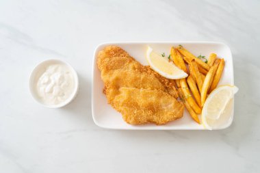 balık ve patates kızartması - kızarmış balık fileto patates cipsi ve limonlu beyaz tabak