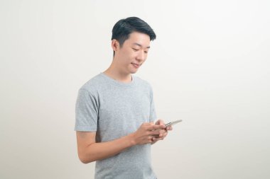 Beyaz arka planda akıllı telefon ve cep telefonu kullanan ya da konuşan genç Asyalı adam