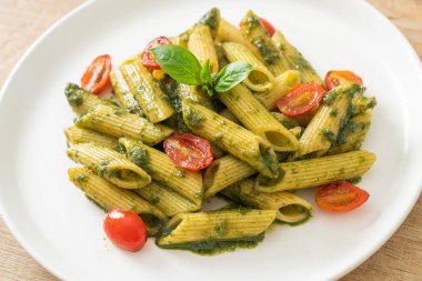 Pesto soslu ve domatesli makarna. Vejetaryen ve vejetaryen yemek tarzı.