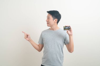 Beyaz arka planda kredi kartı tutan genç Asyalı adam portresi