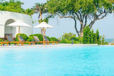 Okyanus geçmişi olan yüzme havuzunun etrafında havuzu olan şemsiyeler - tatil ve tatil kavramı