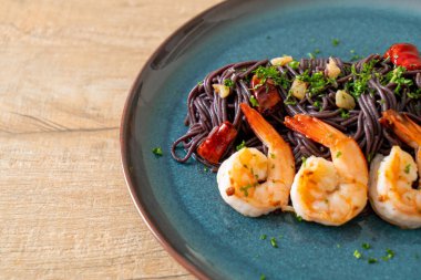 Sarımsaklı ve karidesli kızarmış siyah spagetti.