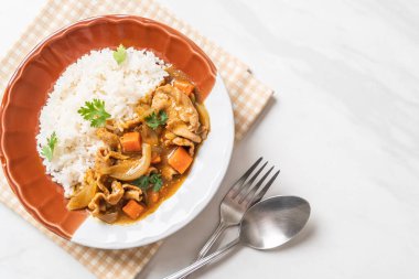 Dilimlenmiş domuz eti, havuç ve soğanlı Japon körili pilavı. Asya usulü.