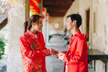 Mutlu genç Asyalı çiftler geleneksel Çin elbiseleriyle sevişir. Kırmızı, geleneksel bayramın ana rengidir. Buna Çin 'de düğün de dahil..