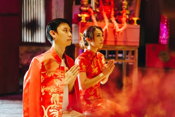 Happy young Asian couple love in Chinese traditional dresses praying at Chinese temple