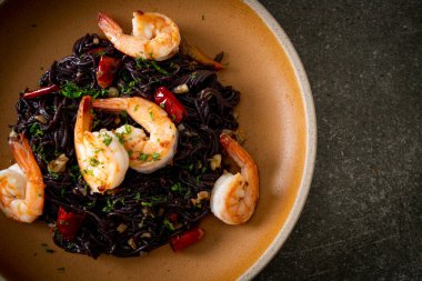 Sarımsaklı ve karidesli kızarmış siyah spagetti.