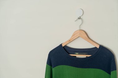 colorful sweater hanging with wood hanger on wall