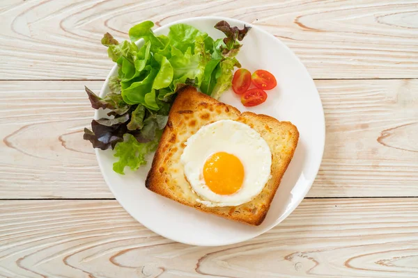 homemade bread toasted with cheese and fried egg on top with vegetable salad for breakfast