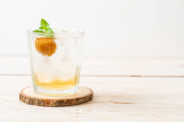 iced plum juice with soda and peppermint on wood table - refreshment drink