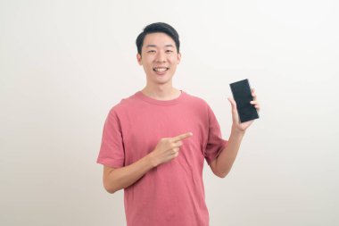 Genç Asyalı adam beyaz arka planda mutlu yüzlü akıllı telefon ve cep telefonu kullanıyor veya konuşuyor