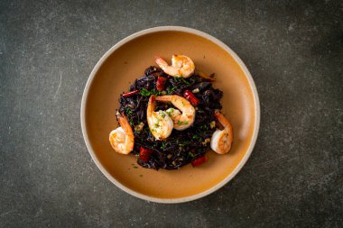 Sarımsaklı ve karidesli kızarmış siyah spagetti.