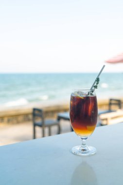 Okyanus arkaplanlı buzlu americano kahve şeftalisi.