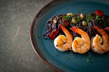 Sarımsaklı ve karidesli kızarmış siyah spagetti.