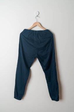 Pantolon ya da uzun pantolon duvarda ahşap askıyla asılı.