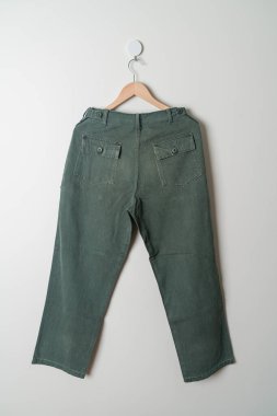 Pantolon ya da uzun pantolon duvarda ahşap askıyla asılı.