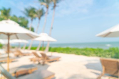 Arka planda plaj sandalyesi ve okyanus denizi olan soyut bulanık şemsiye