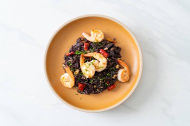 Sarımsaklı ve karidesli kızarmış siyah spagetti.