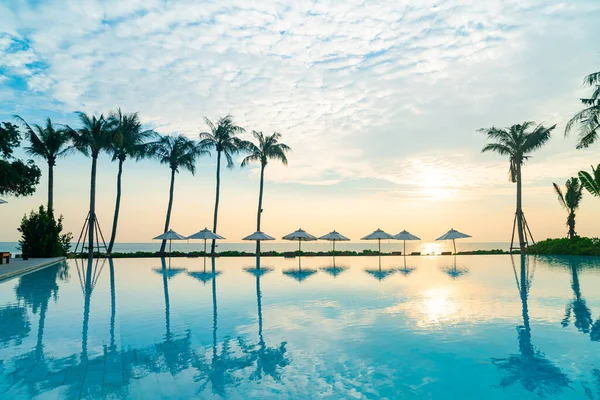 umbrella with bed pool around swimming pool with ocean sea background at sunset or sunrise time - holiday and vacation concept