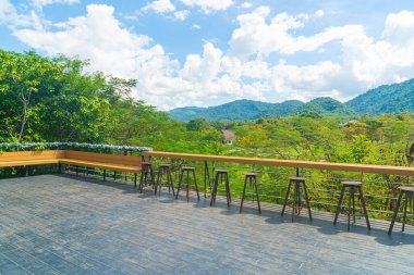 Balkonda boş bir bank ve bar taburesi var.
